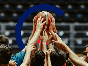 A group of basketballers holding up a basketball together, with the Coordinate Sport logo in the background